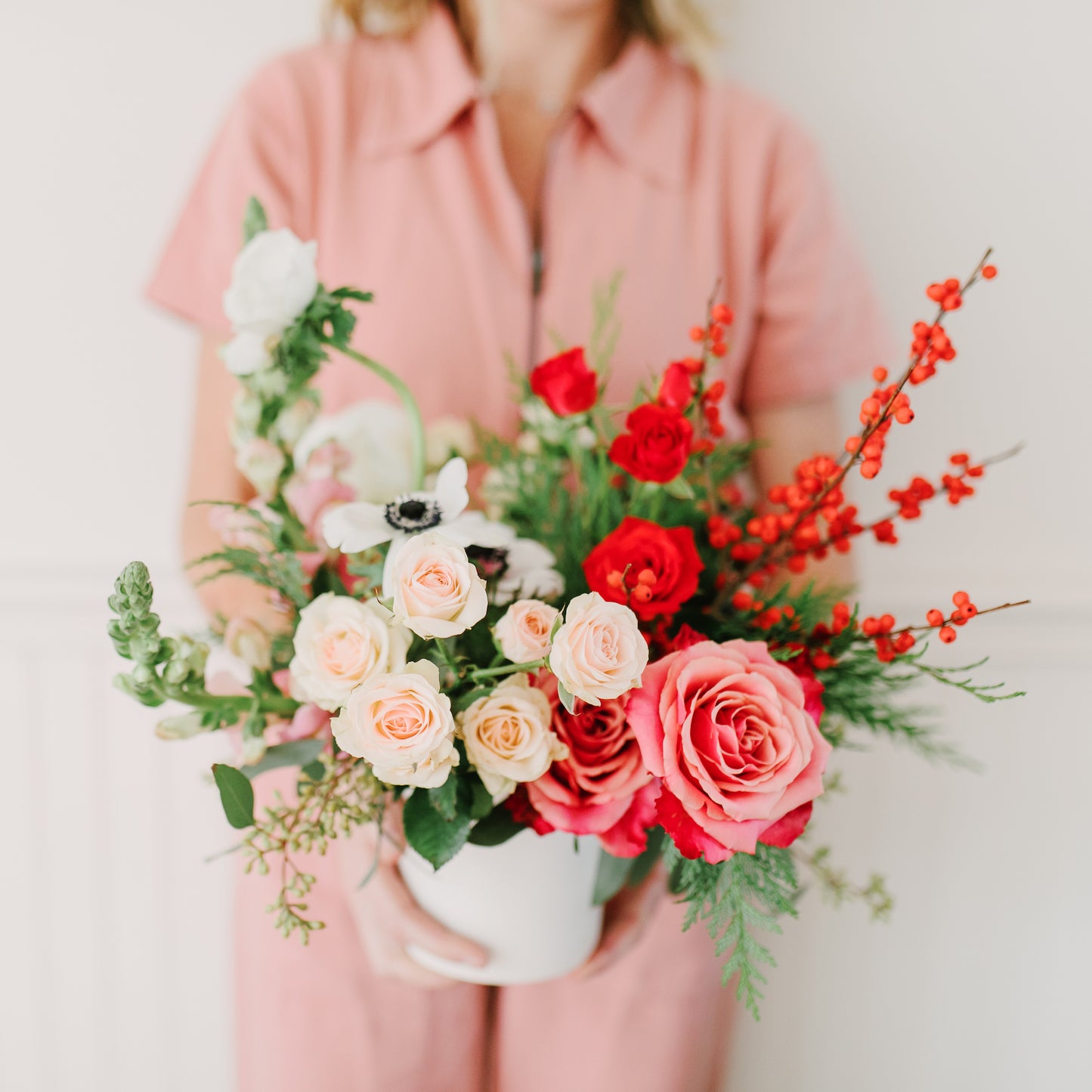 Woman holds a holiday floral centerpiece with pink and red flowers
