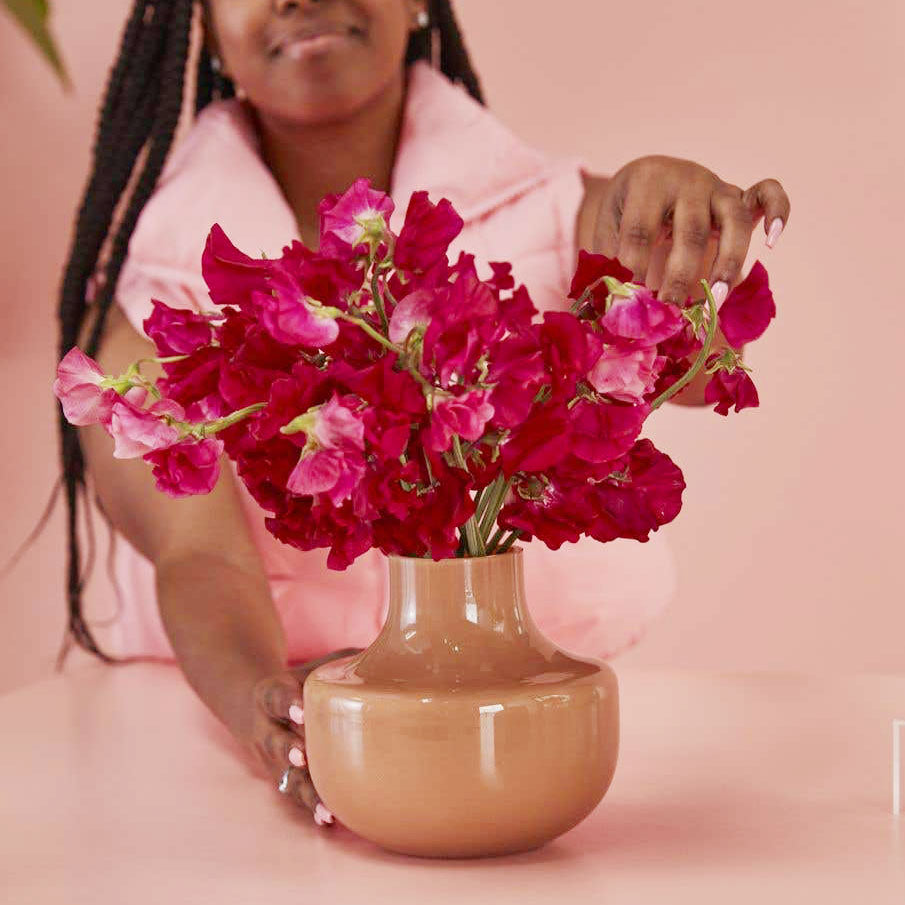 Florist arranges magenta flowers in Alma Glass Vase
