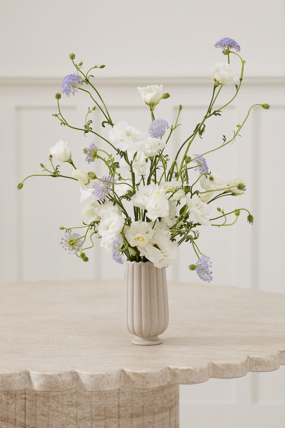 Floral arrangement in a silver vase on a light surface with a neutral background