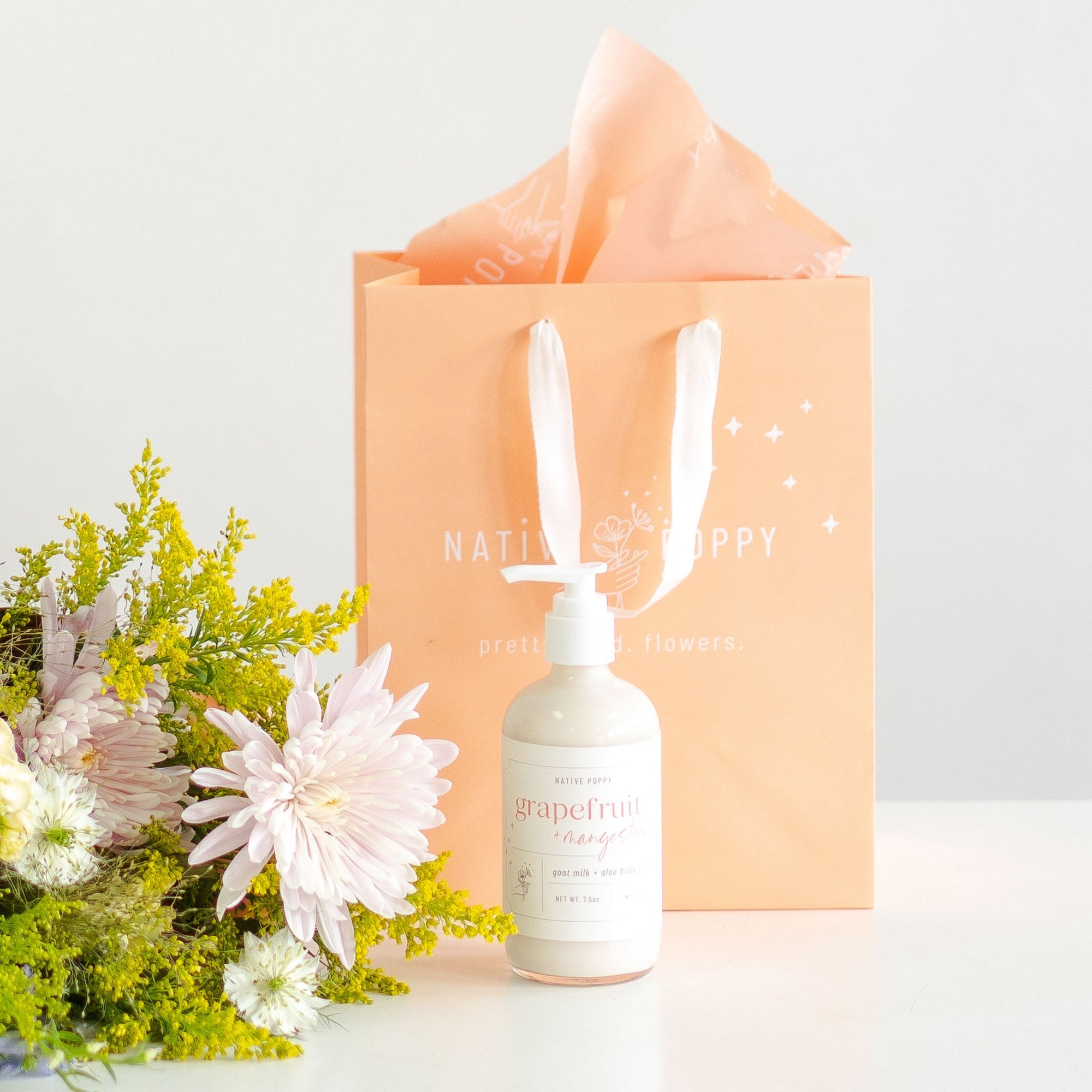 Grapefruit lotion with a peach native poppy gift bag and flowers