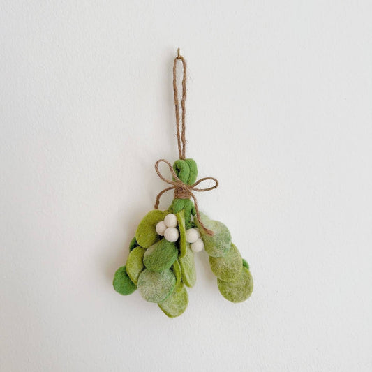 Decorative mistletoe ornament with white berries on a plain background