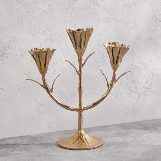 Gold candelabra with three branches on a gray surface and light gray background