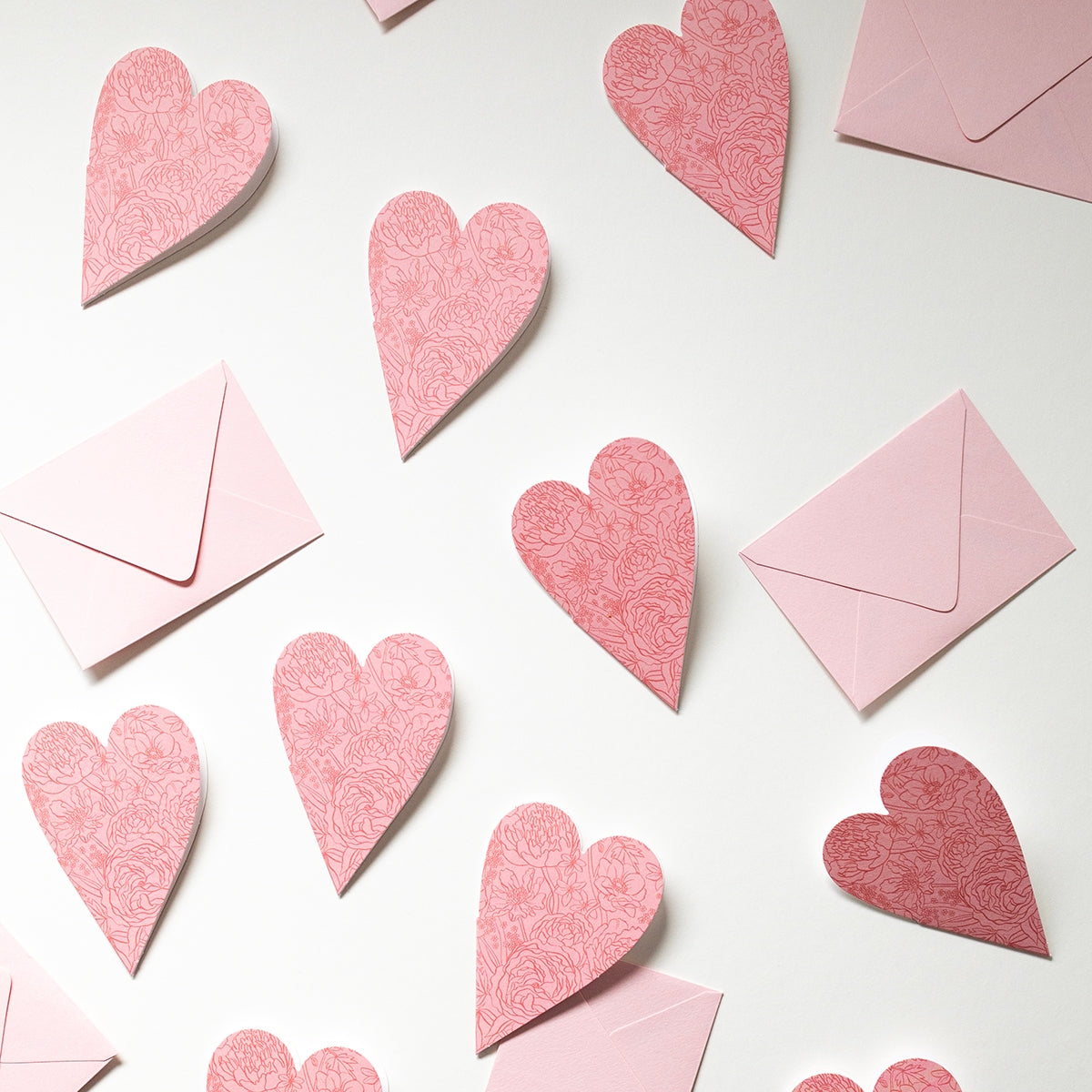 Pink heart-shaped cards and envelopes on a white background