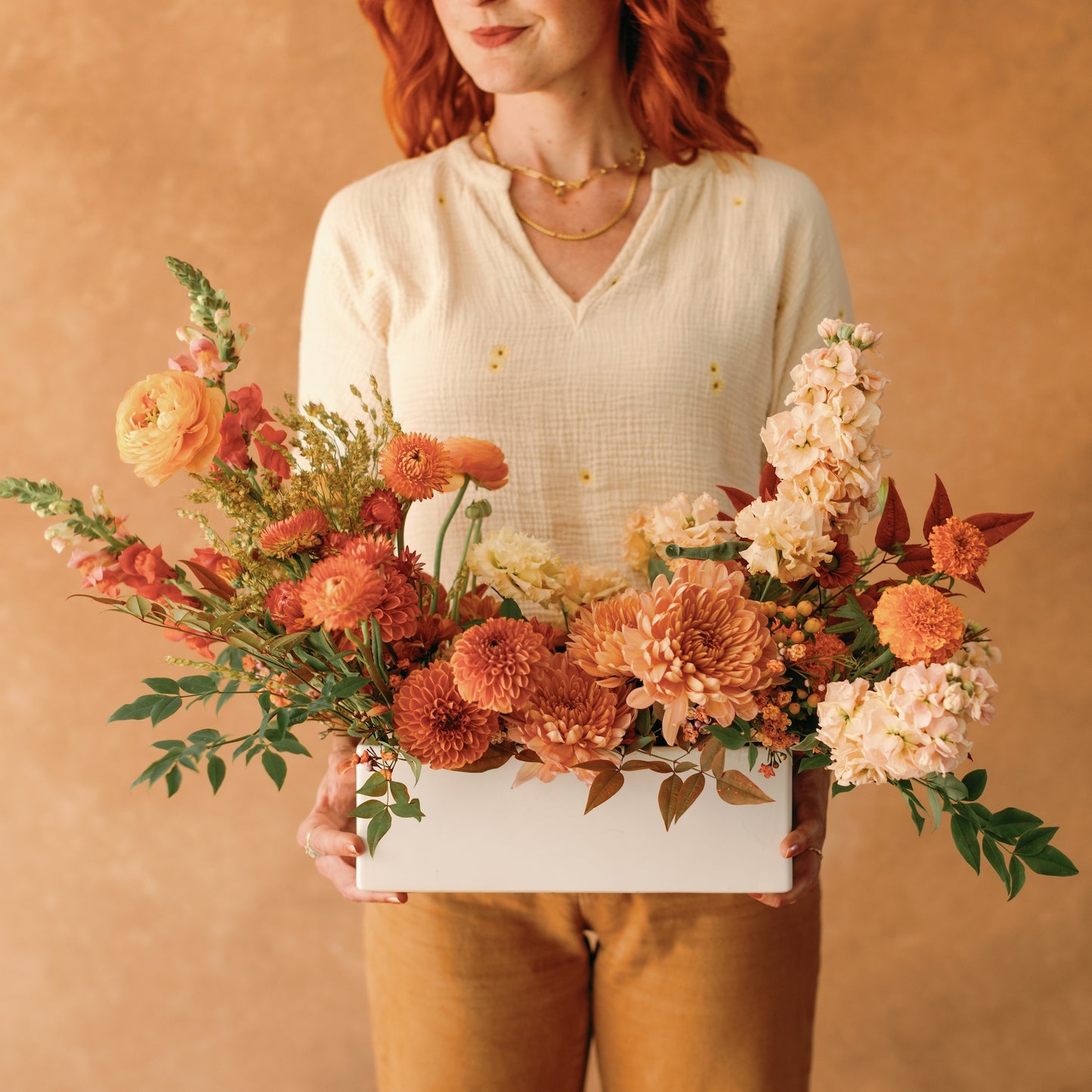Woman holds thanksgiving long and low flower arrangement from native poppy