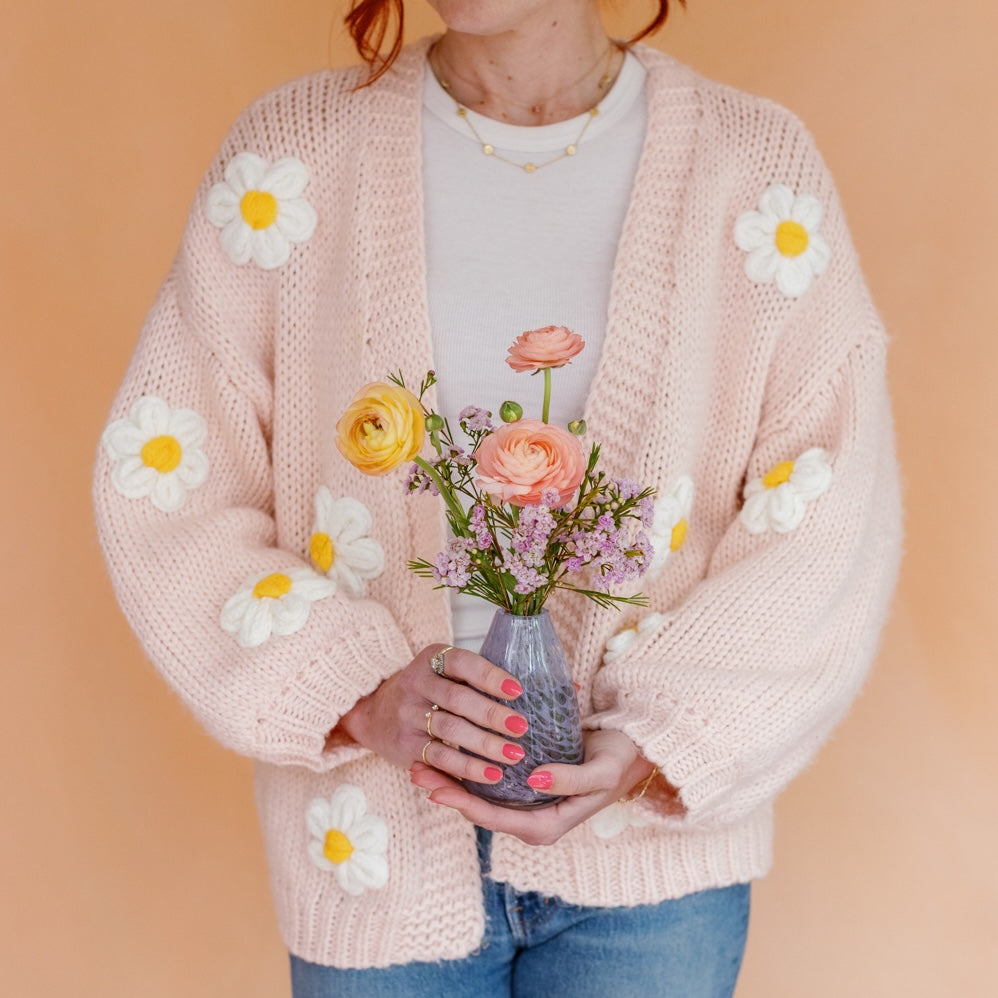 Woman in floral sweater holds a bud vase arrangement