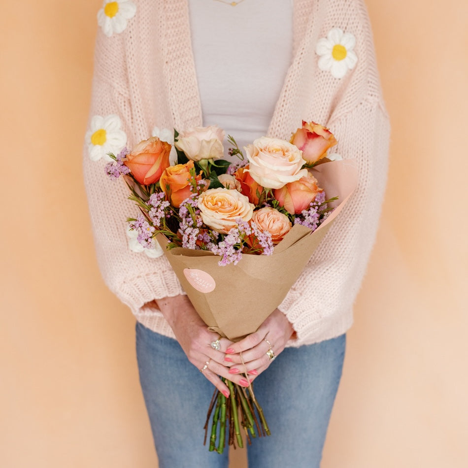 Woman holding a bouquet of peach roses from Native Poppy in San Diego