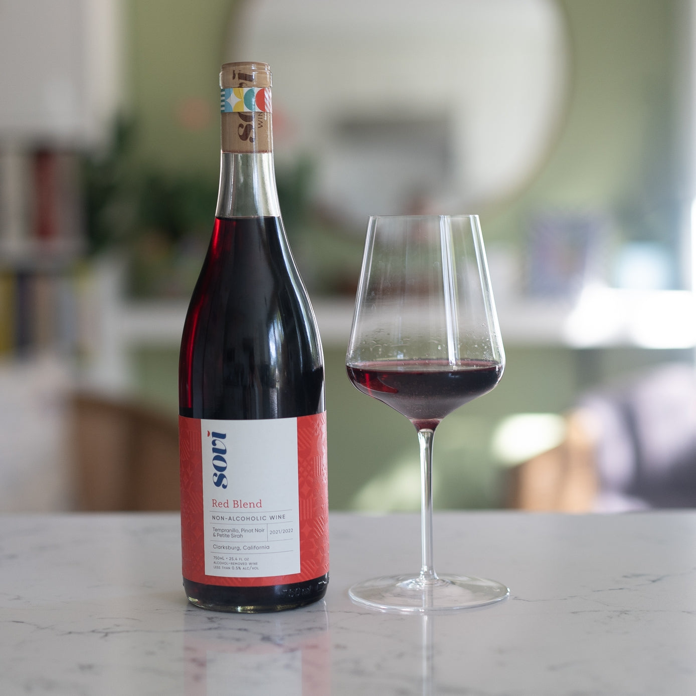 Bottle of red wine with a glass on a marble surface, blurred background