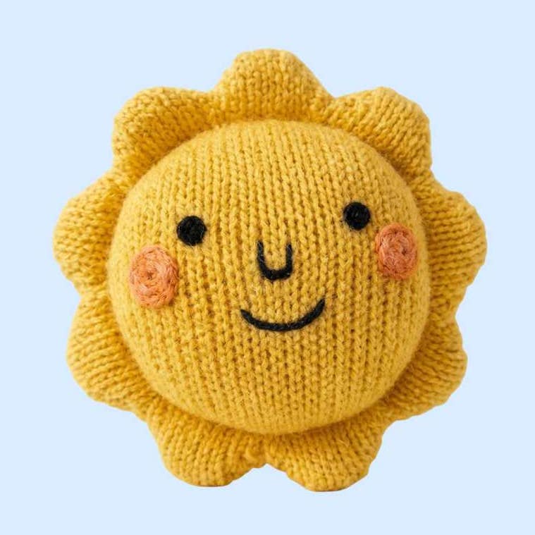 Knitted sun-shaped toy with a smiling face on a light blue background