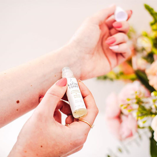 A woman applies Native Poppy rollerball perfume to wrist