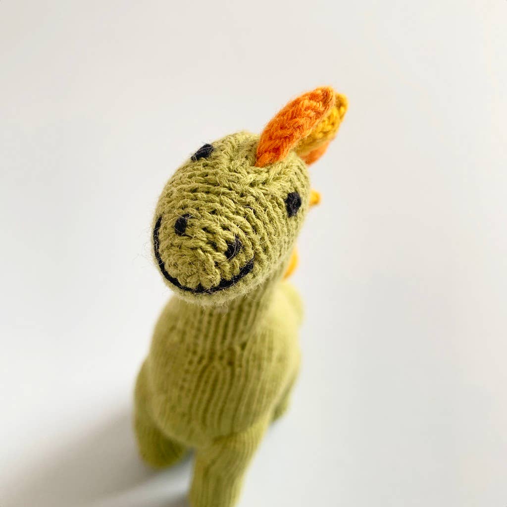 Black embroidered smiley face details on green knitted dino toy