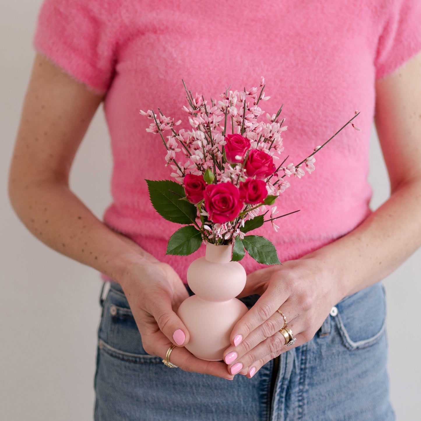 Woman holding Small pink bud vase filled with pink flowers