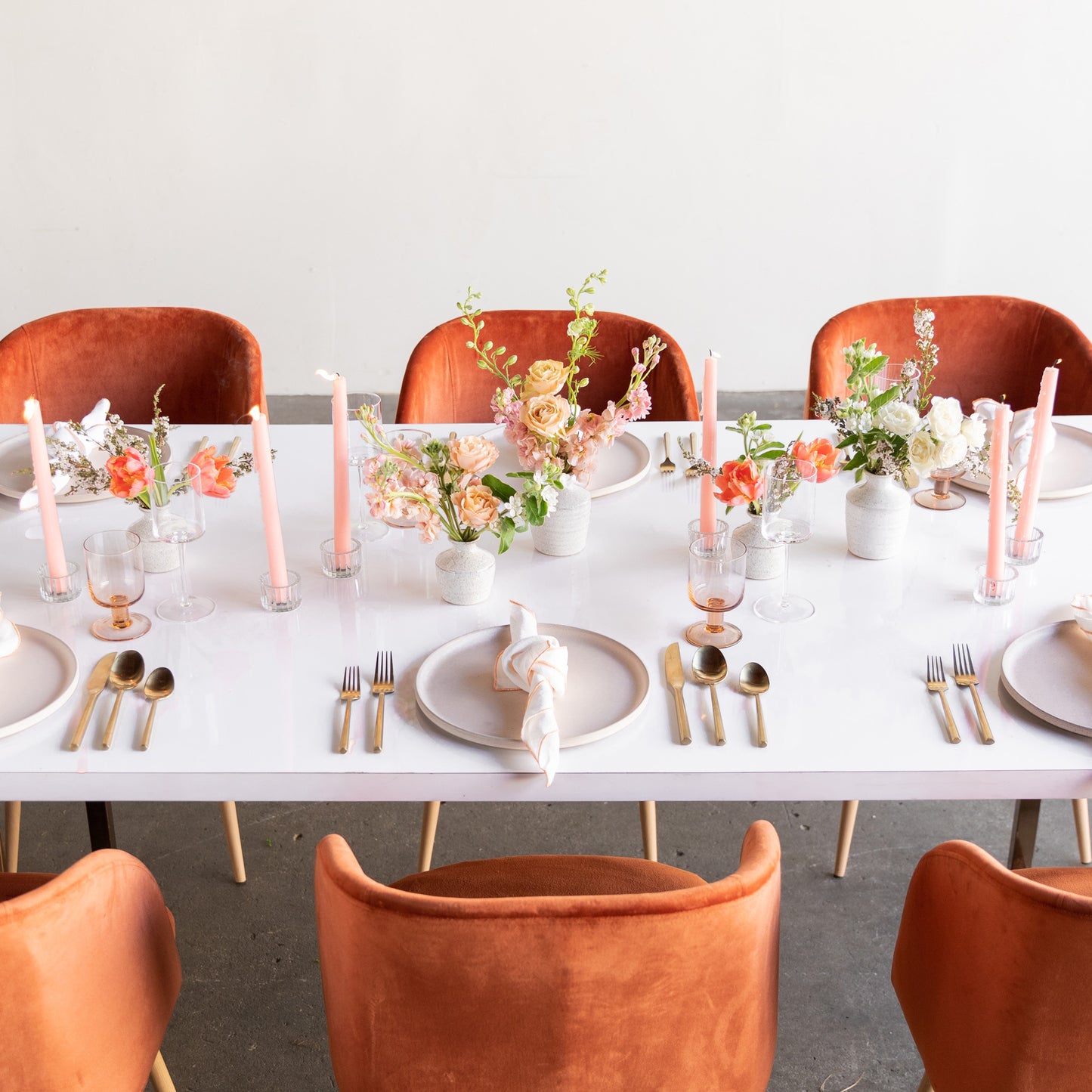 Bud vase arrangements decorate a formal table setting with pink candles