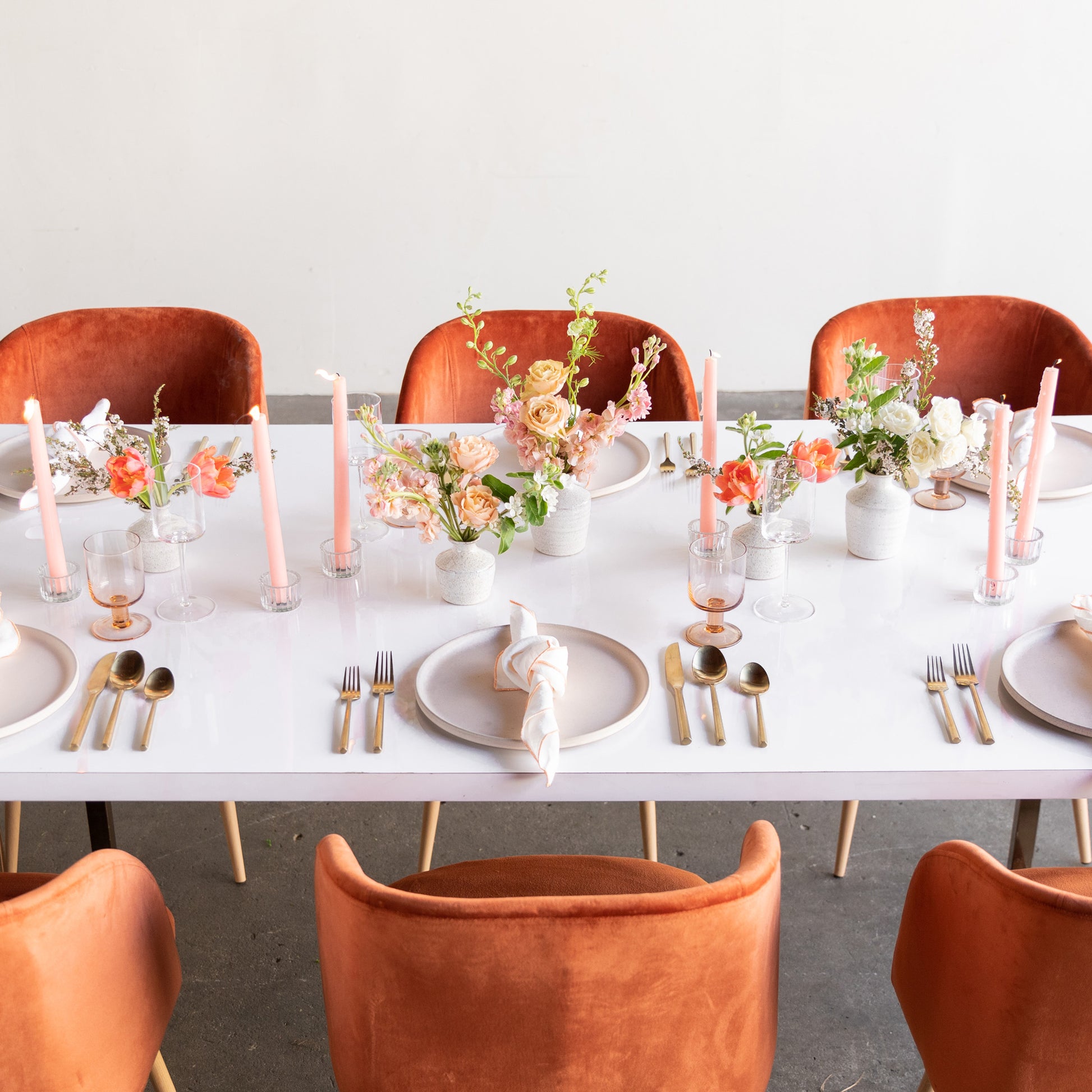 Bud vase arrangements decorate a formal table setting with pink candles