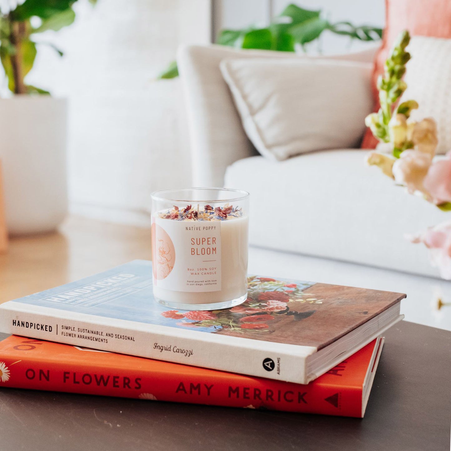 Super Bloom candle on top of flower books on a coffee table