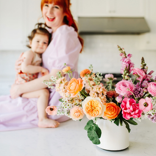 Mother posing in a purple dress with children next to flowers