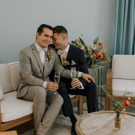 Two men embrace after their wedding, surrounded by flower arrangements