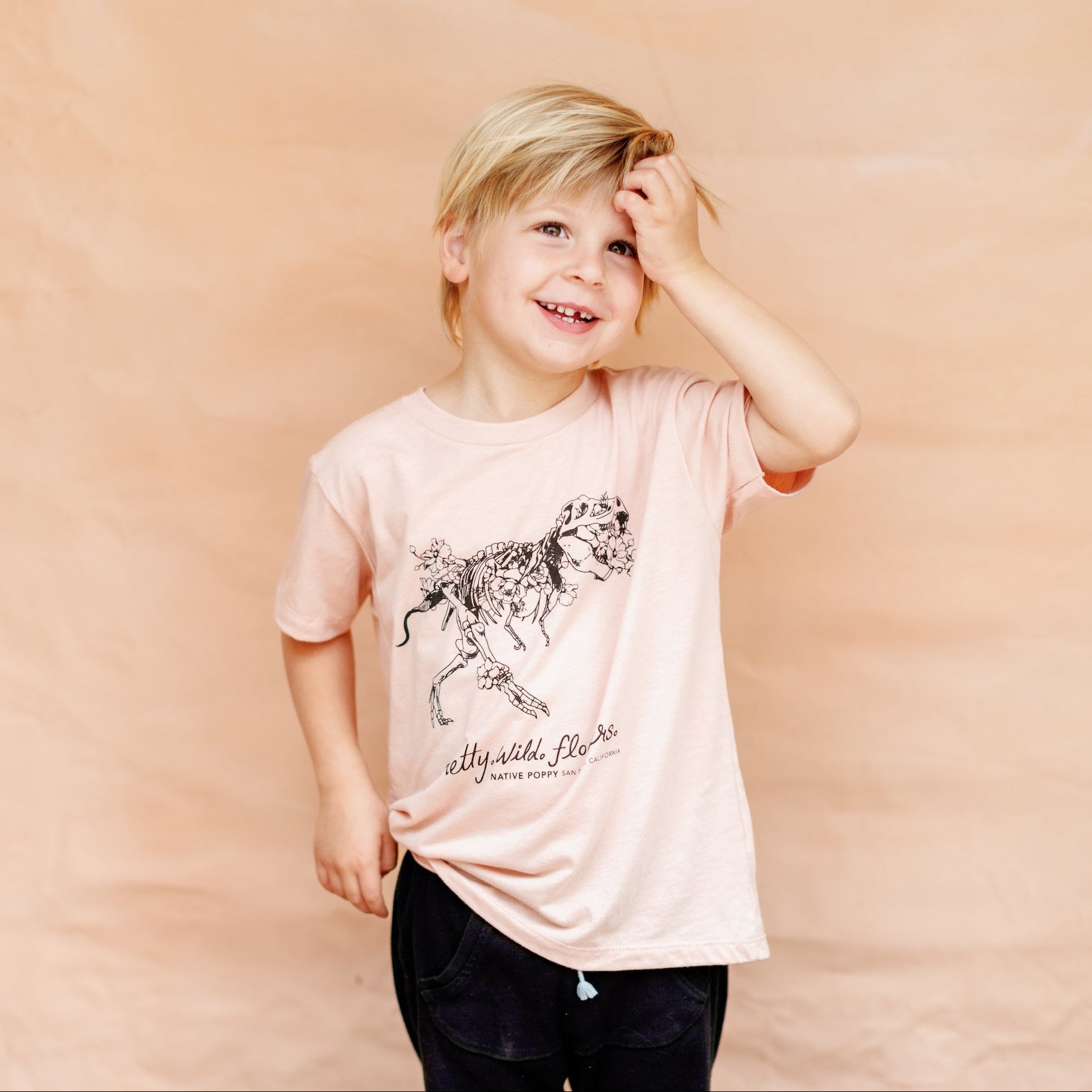 Young child wearing a peach florasaurus toddler tee