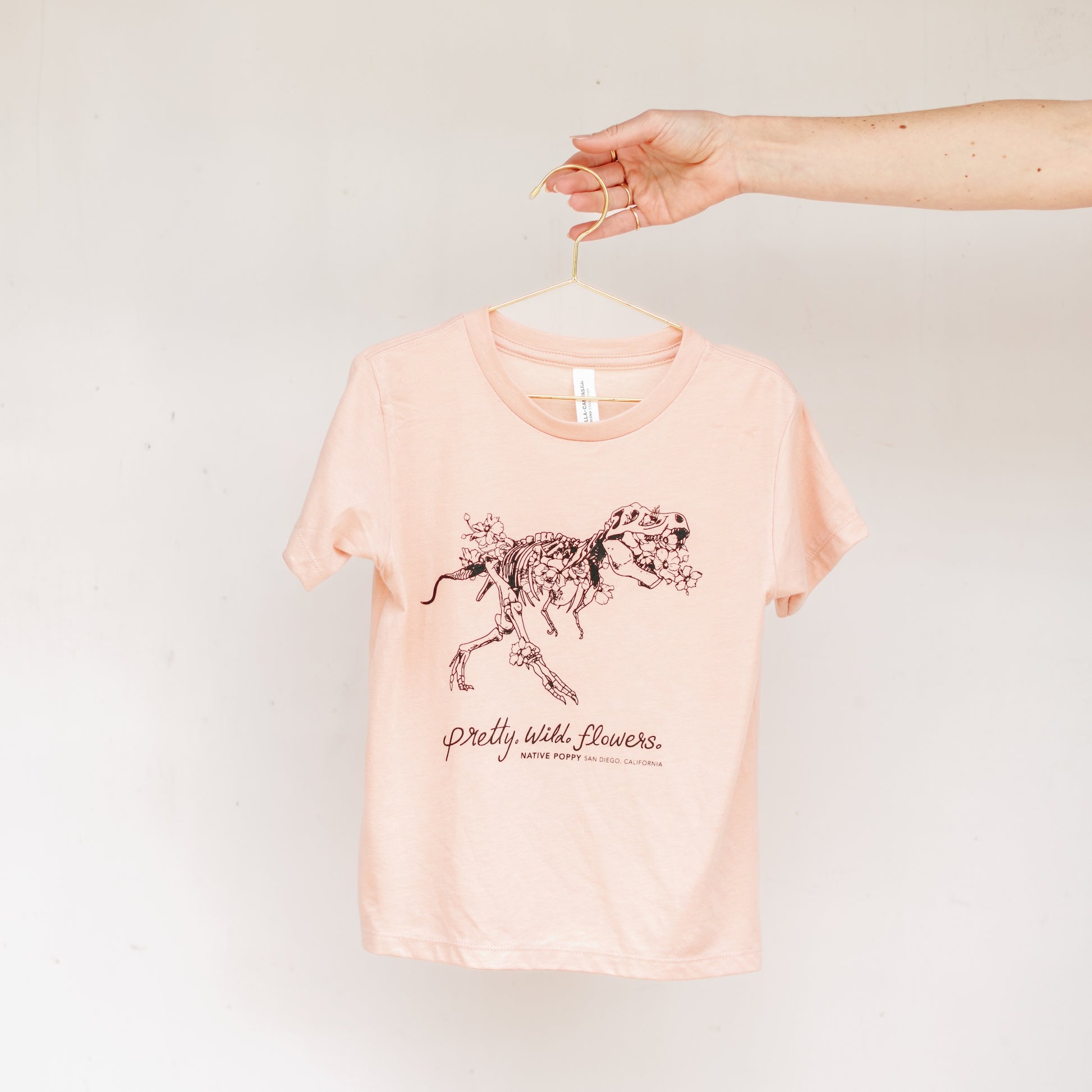 Peach toddler tee with a t-rex illustration