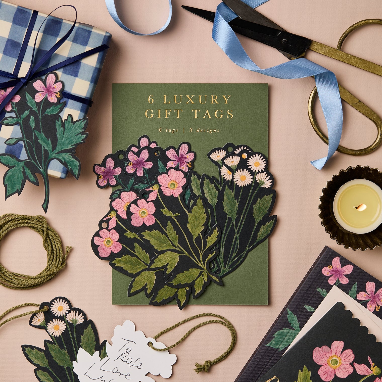 Floral gift tags on a beige surface with ribbons and scissors.