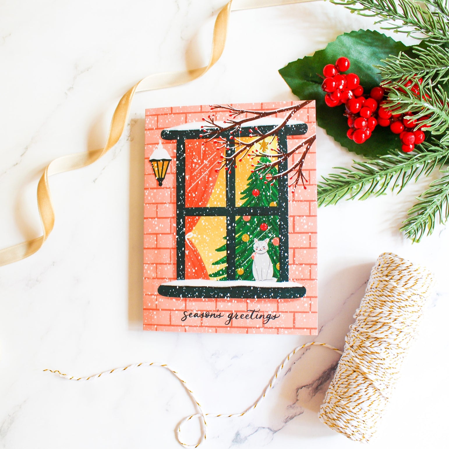 Christmas-themed greeting card with a window, tree, and cat, surrounded by festive decorations on a white background.