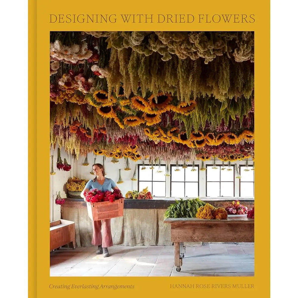Book cover of 'Designing with Dried Flowers' with woman holding flowers and hanging dried flowers on a yellow background