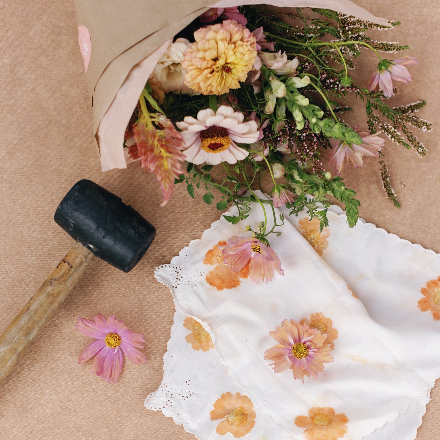 Bouquet of flowers, a hapazome printed napkin, and a mallet on a brown surface