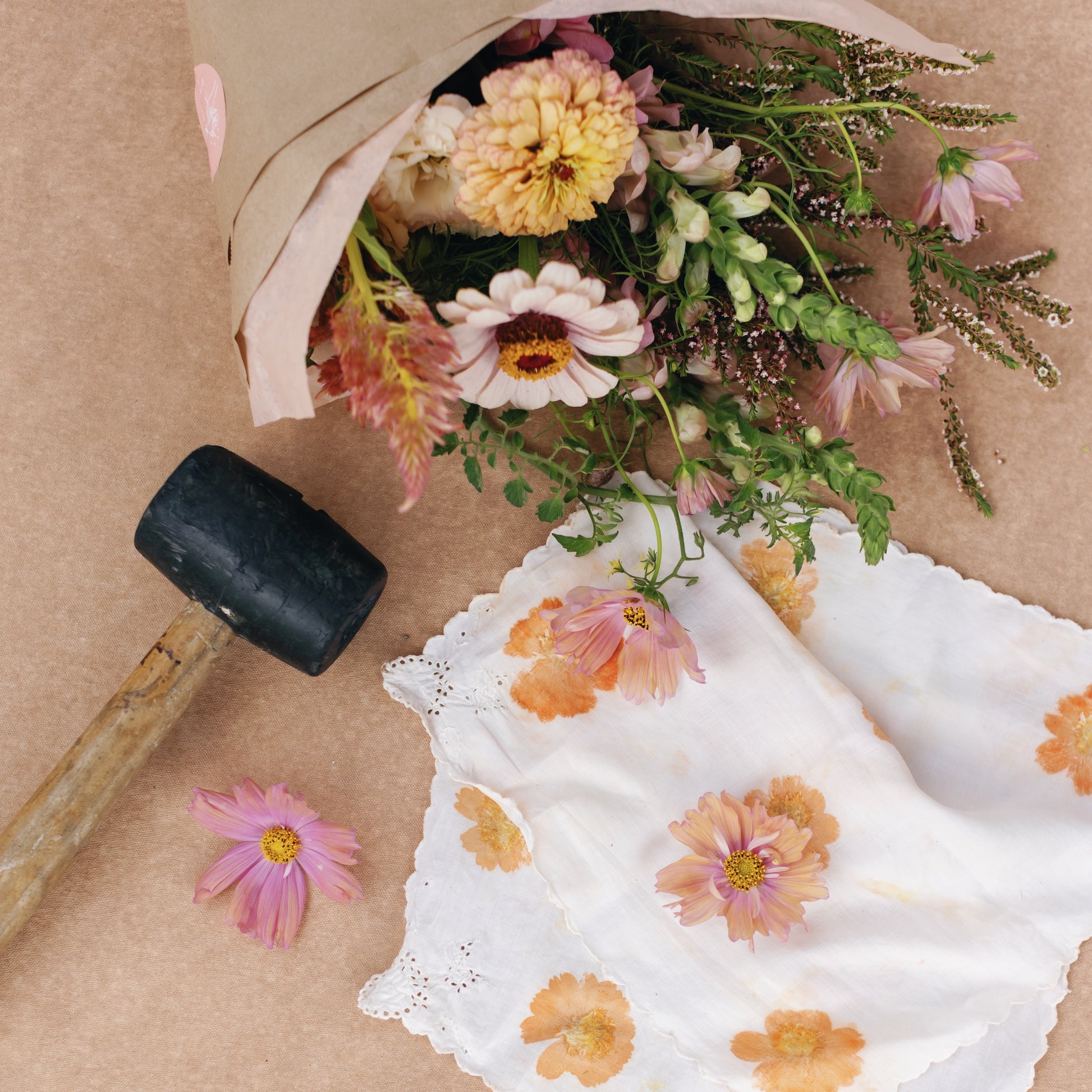 Bouquet of flowers, a hapazome printed napkin, and a mallet on a brown surface