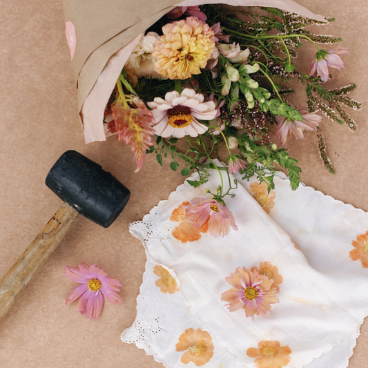 Bouquet of flowers, a hapazome printed napkin, and a mallet on a brown surface