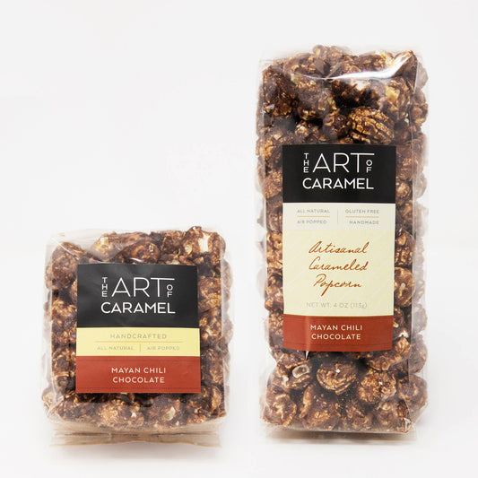 Two packages of 'The Art of Caramel' Mayan Chili Chocolate popcorn on a white background