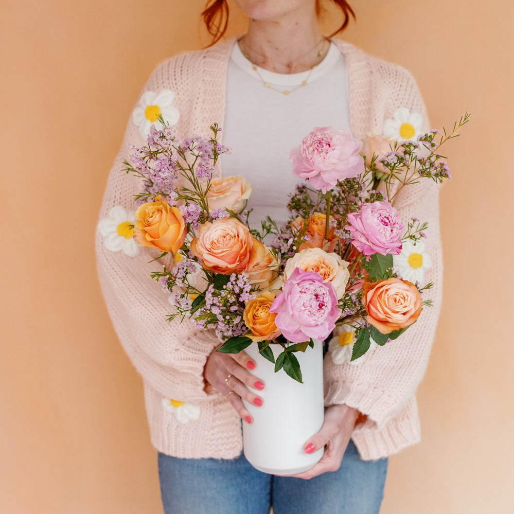 Woman holds peony and rose arrangement