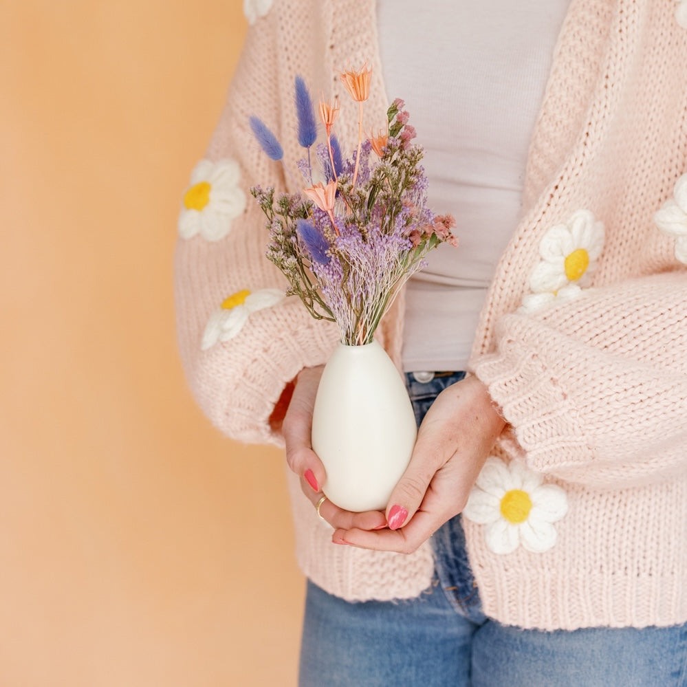 Woman holds a peach, lilac, and lavender dried bud vase arrangement