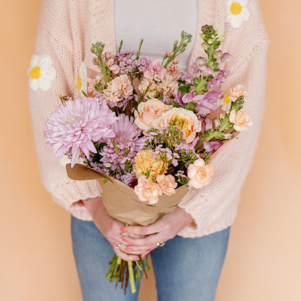 Woman holds Mother's Day flower wrap from Native Poppy in shades of peach, pink, and purple