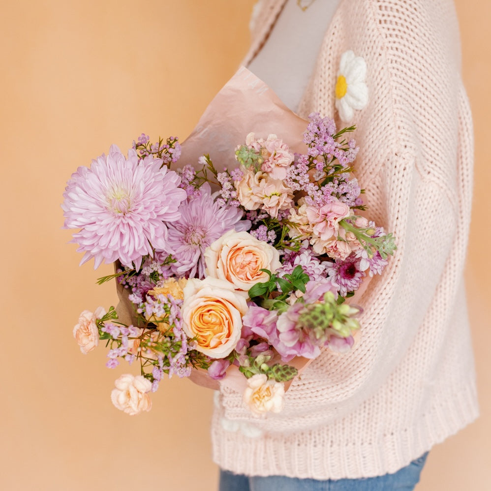 Woman holds Mother's Day flower wrap from Native Poppy in shades of peach, pink, and purple