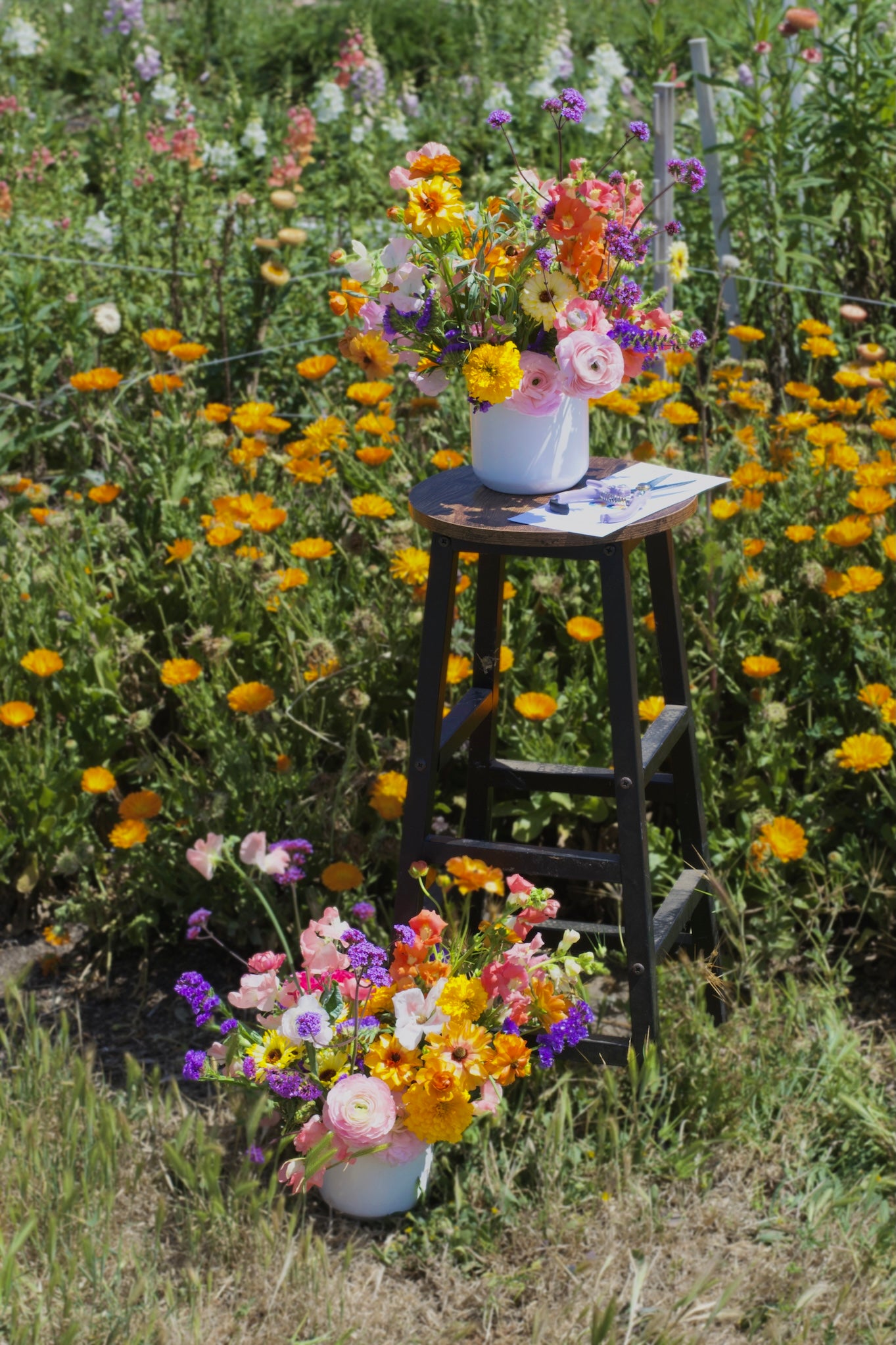 Floral arrangement in a pot on a wooden stool amidst a field of flowers