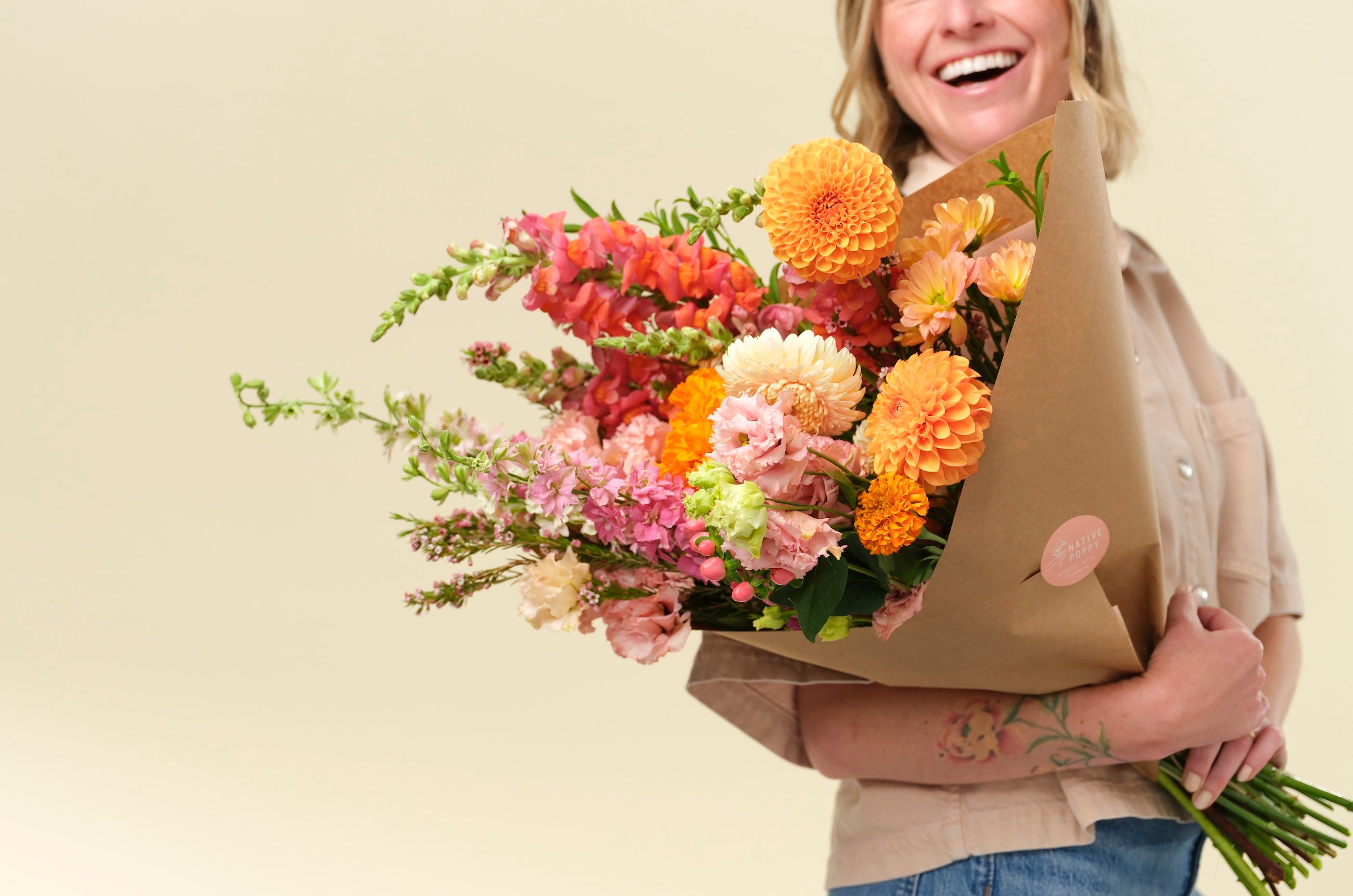 Bouquet of bright, warm-toned flowers held by Native Poppy founder Natalie Gill 