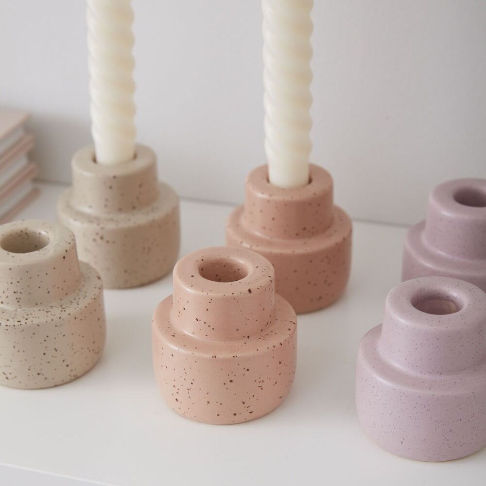 Set of speckled ceramic candle holders in various colors on a white surface.