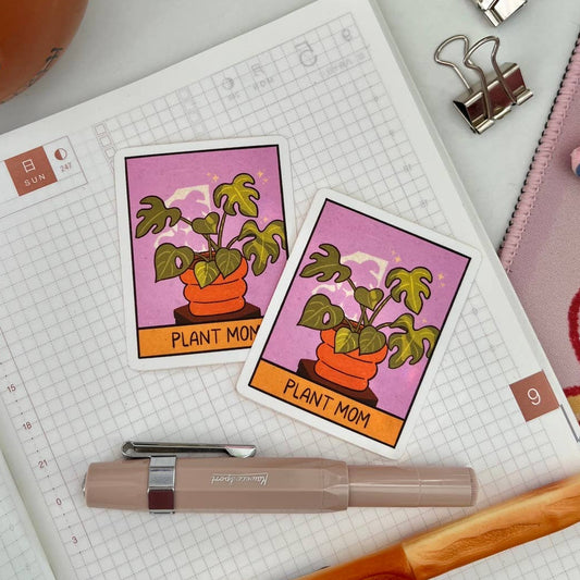 Notebook with plant-themed cards, pen, and stationery items on a desk.