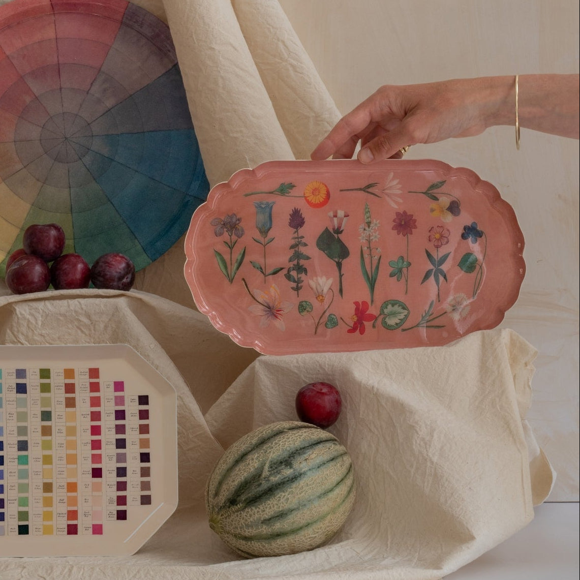 Color swatch chart, decorative plate with floral design, and other items on a neutral background