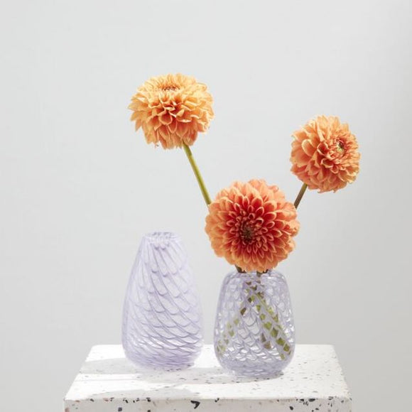 Two purple glass bud vases with orange dahlias
