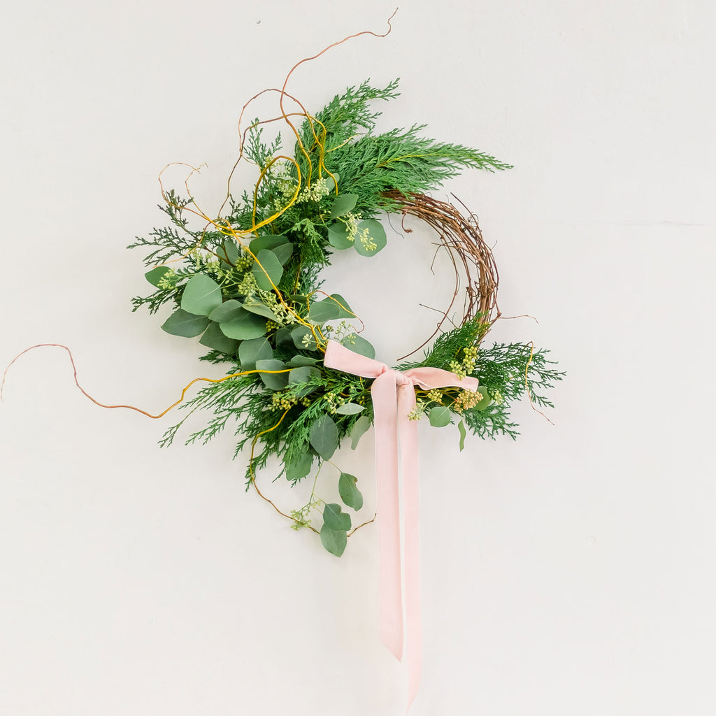 Winter Forest Wreath made with cedar and eucalyptus, tied with pink ribbon