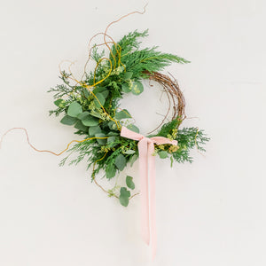 Winter Forest Wreath made with cedar and eucalyptus, tied with pink ribbon