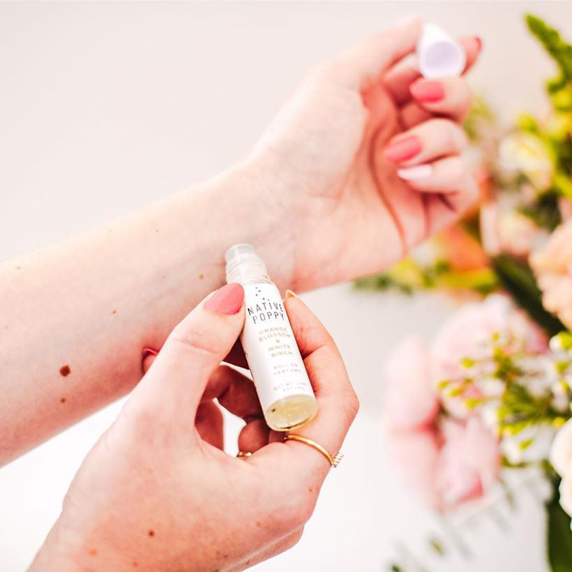 A woman applies Native Poppy rollerball perfume to wrist