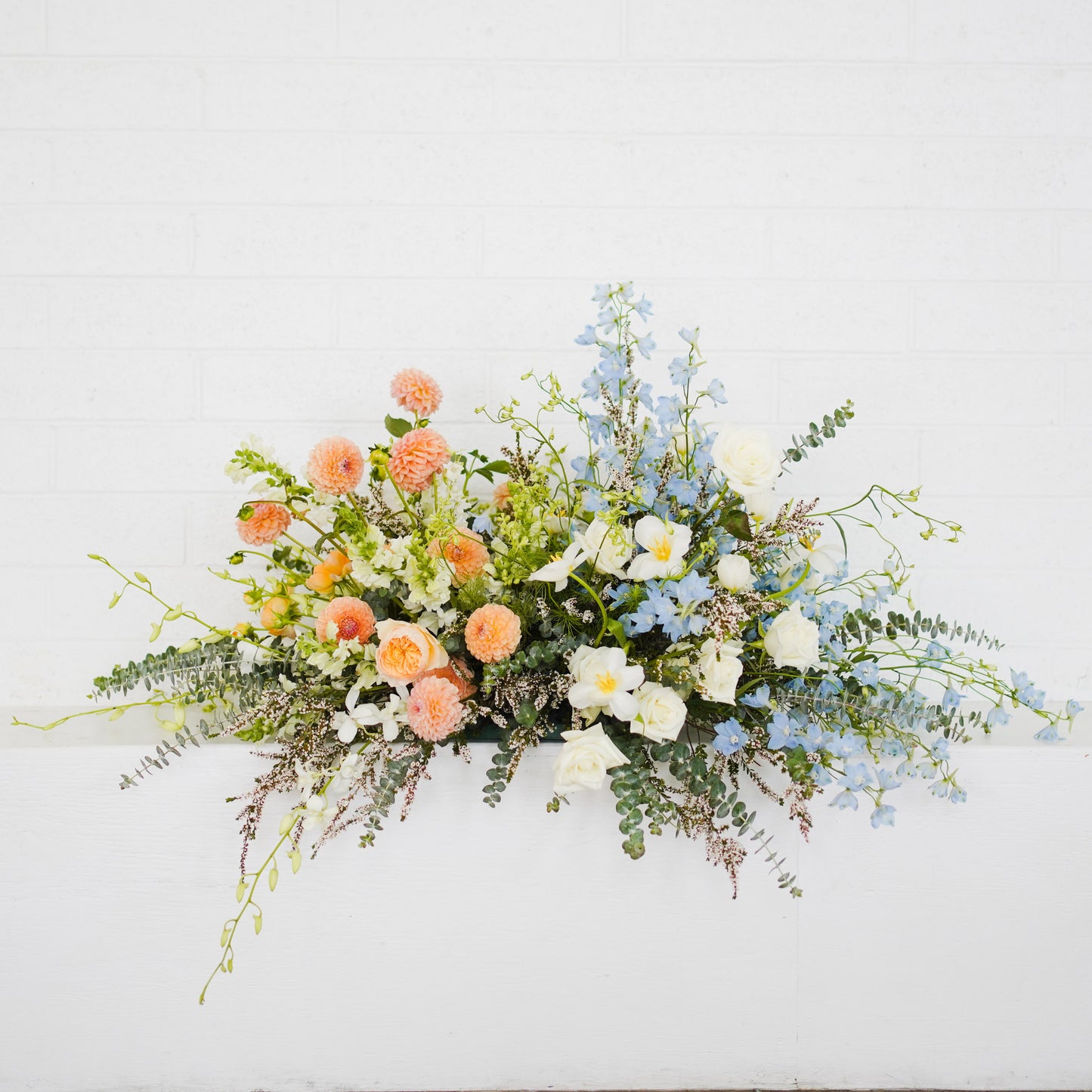 Casket Floral Spray with white, peach, and blue flowers