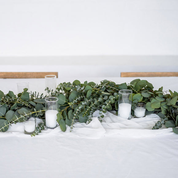 Eucalyptus Greenery Garland on a white tablecloth with votive candles