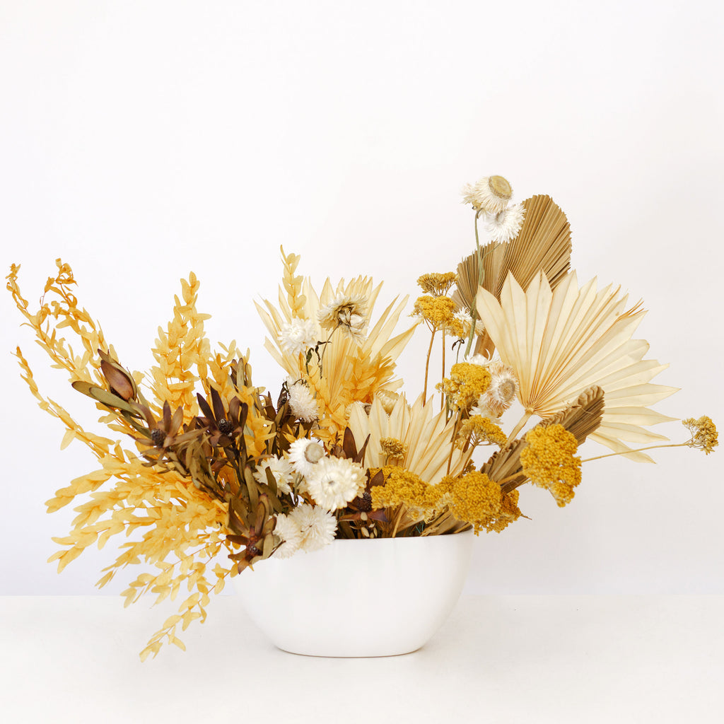 Garden style dried flower arrangement in long white ceramic vase