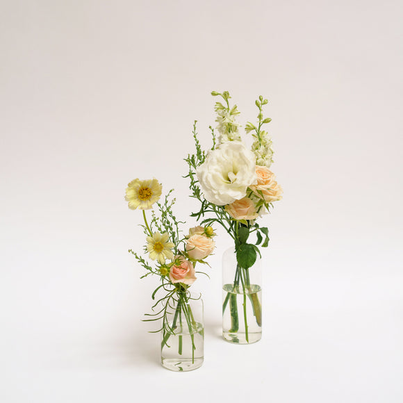 Glass Bud Vases with peach and cream flowers on a white table