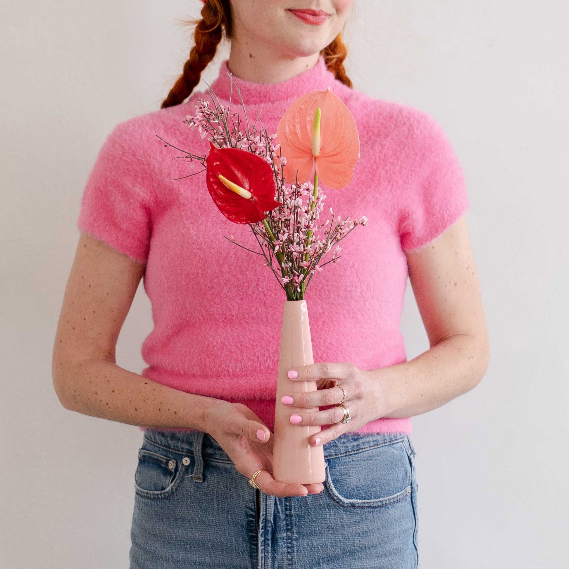 Woman wearing pink holds anthurium arraangement