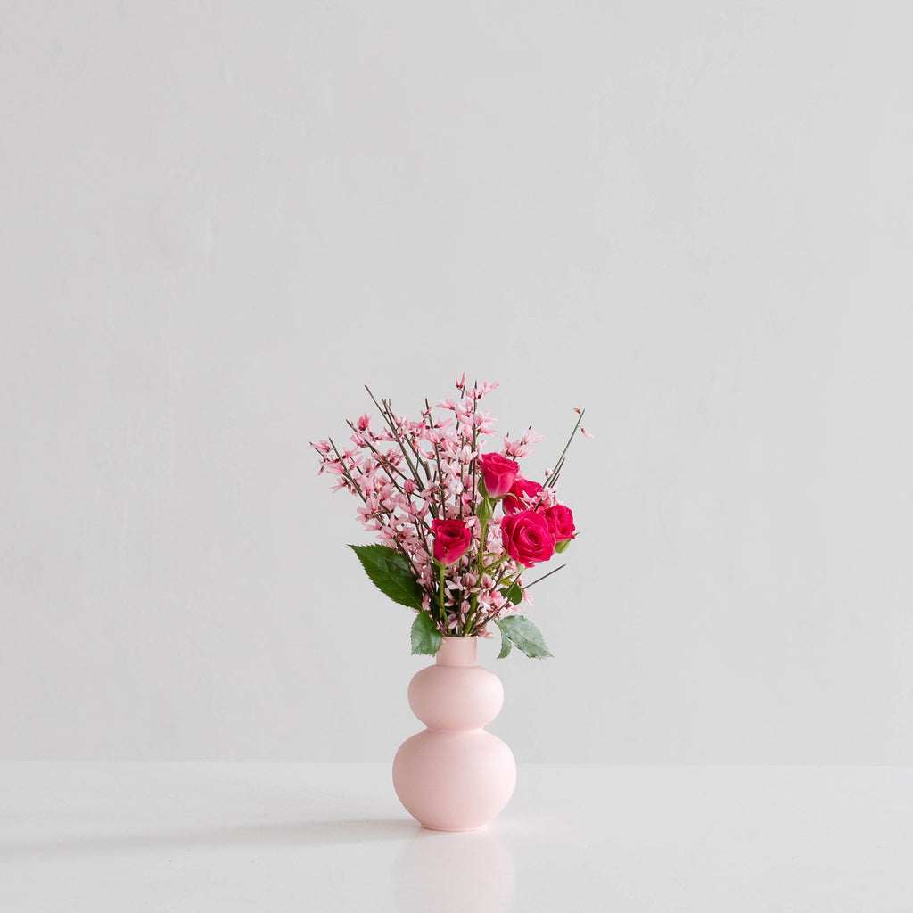 Small pink bud vase filled with pink flowers