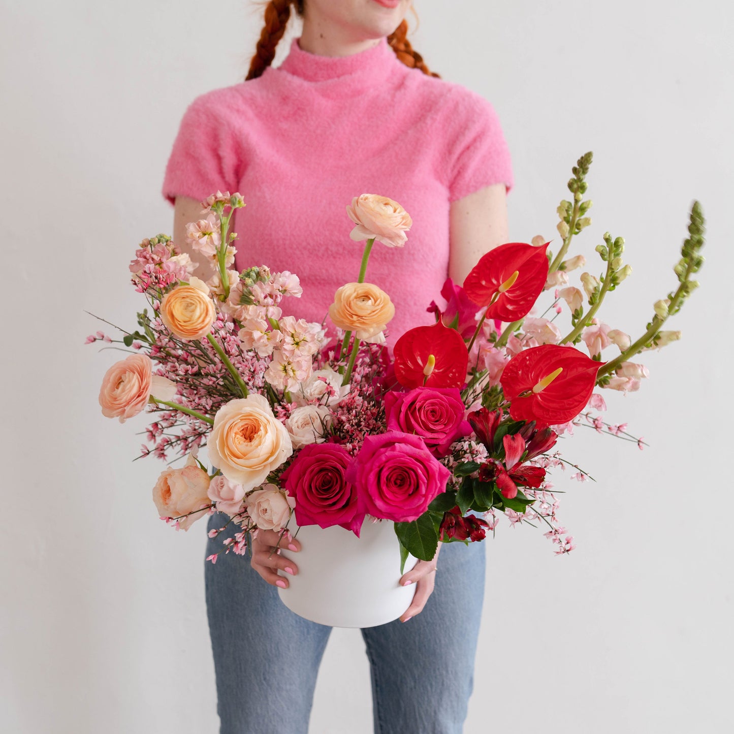 Woman wearing pink holds an extra large Valentine's Day flower arrangement