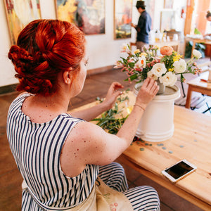 Woman with red hair arranges flowers in a workshop setting
